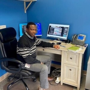 Joseph Genda sits in front of his office desk