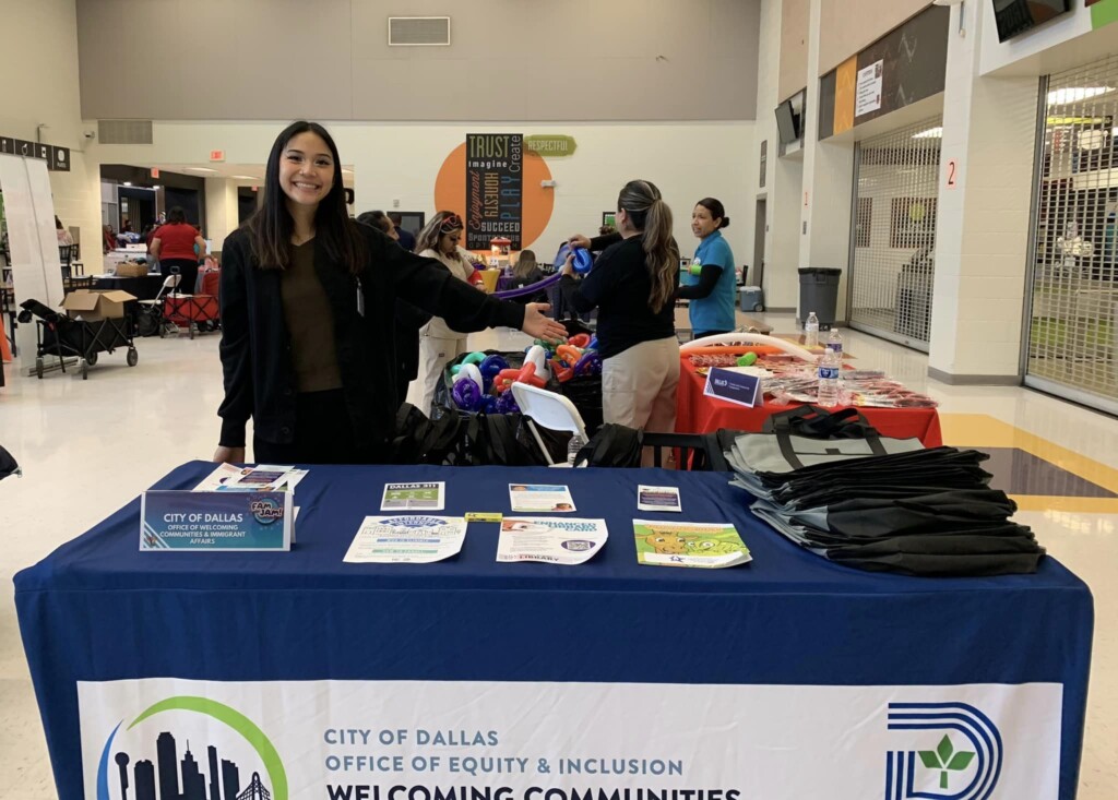 City of Dallas staff member stands at an event table with paper resources for school community members