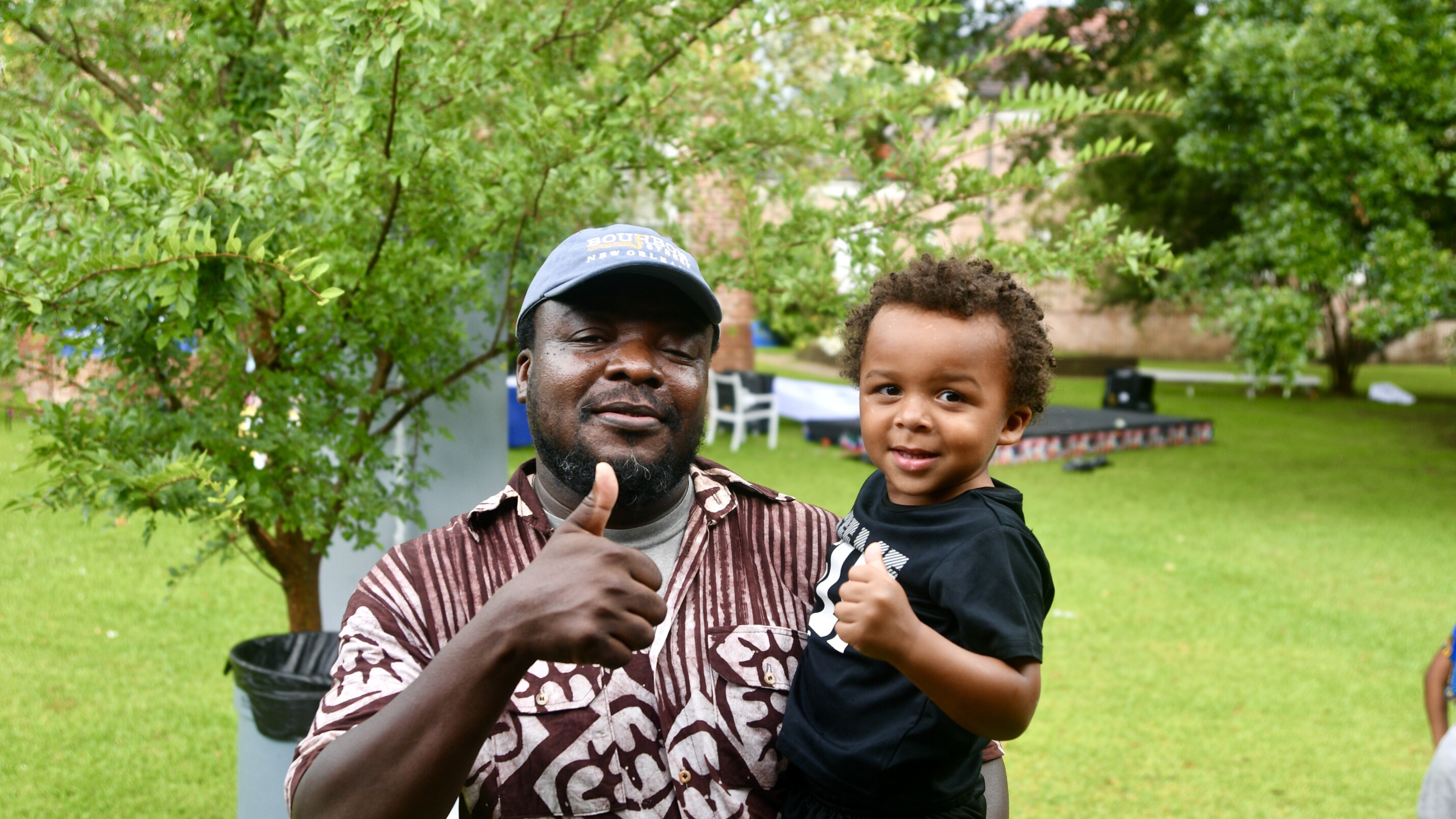 Smiling father and son. The father gives a thumbs up at the camera.